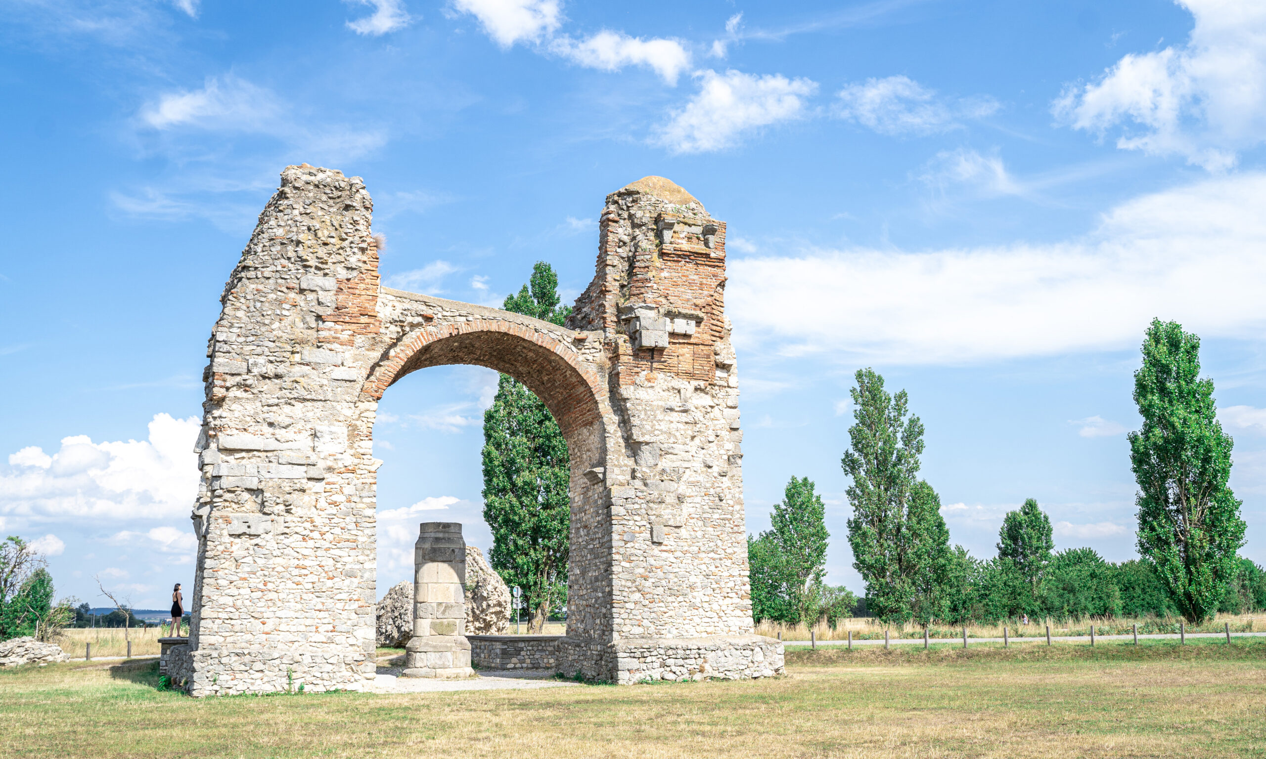 Das Heidentor in Carnuntum – Ruine eines römischen Torbogens in einer Wiese unter blauem Himmel